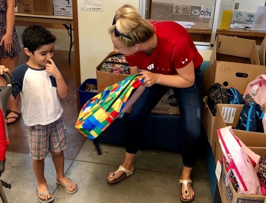 Volunteer and child selecting backpack